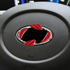 Close-up of a steering wheel trim decal featuring red carbon fiber accents on a black surface.