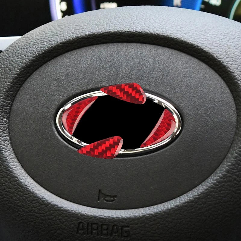 Close-up of a steering wheel trim decal featuring red carbon fiber accents on a black surface.