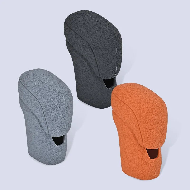 Three gear shift knob covers in dark gray, light gray, and orange colors shown against a light background.