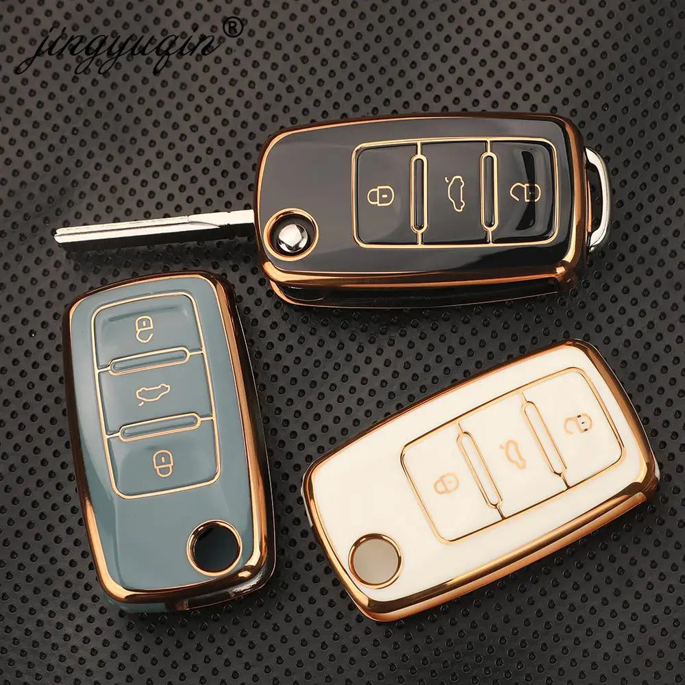 Three silicone TPU car key covers in gold and silver tones displayed on a dark textured surface.