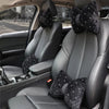 A set of black diamond rhinestone car neck pillows resting on the front seats of a car.