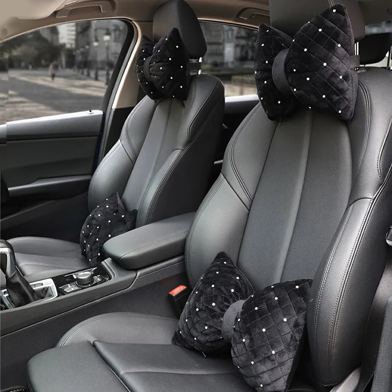 A set of black diamond rhinestone car neck pillows resting on the front seats of a car.