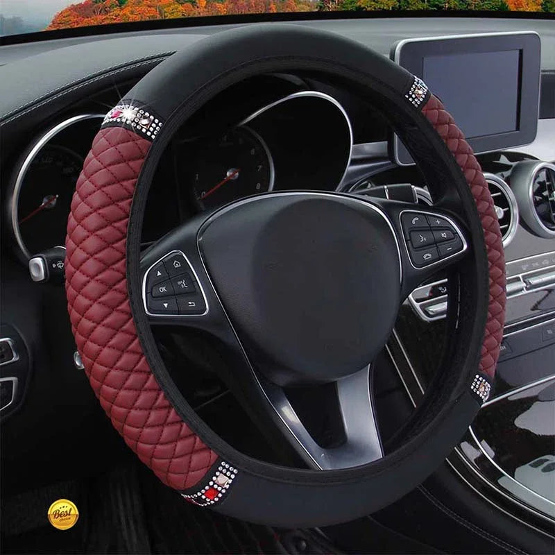 Close-up view of a black steering wheel with a red quilted leather cover and silver accents inside a car interior.