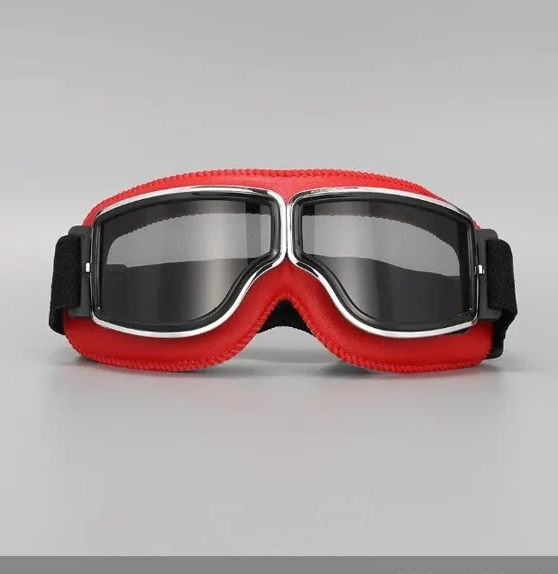 A pair of red and black retro folding motorcycle windproof glasses resting on a gray surface.