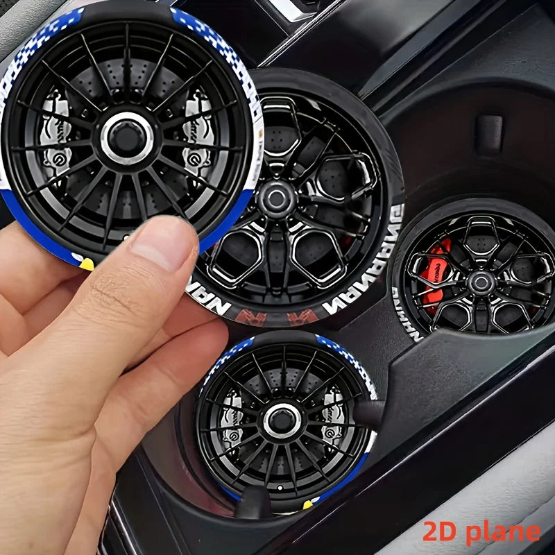 A hand holds a black and blue racing wheel hub design silicone coaster with intricate spokes.