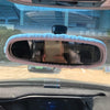 A cartoon plush rearview mirror cover is installed in a vehicle's interior.