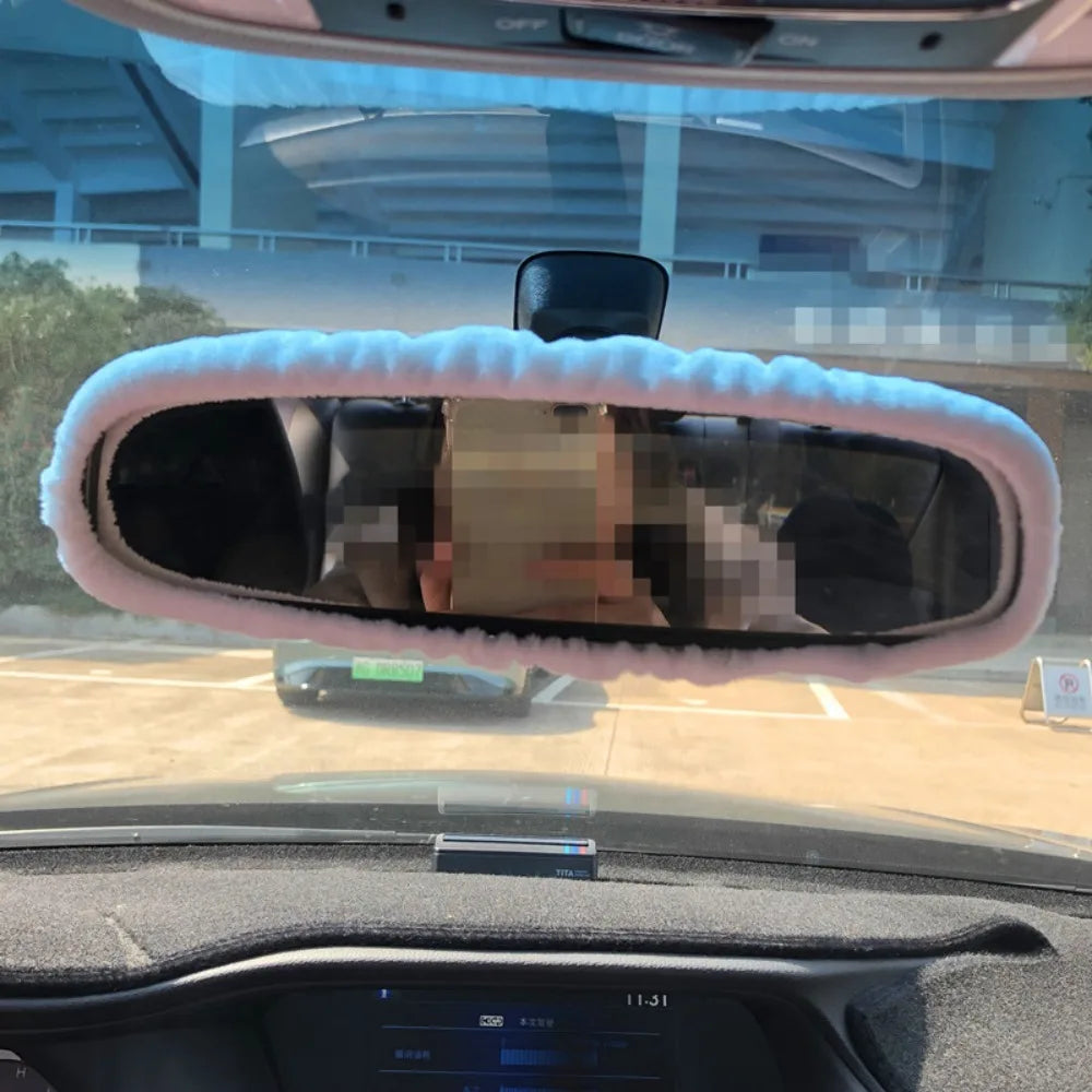 A cartoon plush rearview mirror cover is installed in a vehicle's interior.
