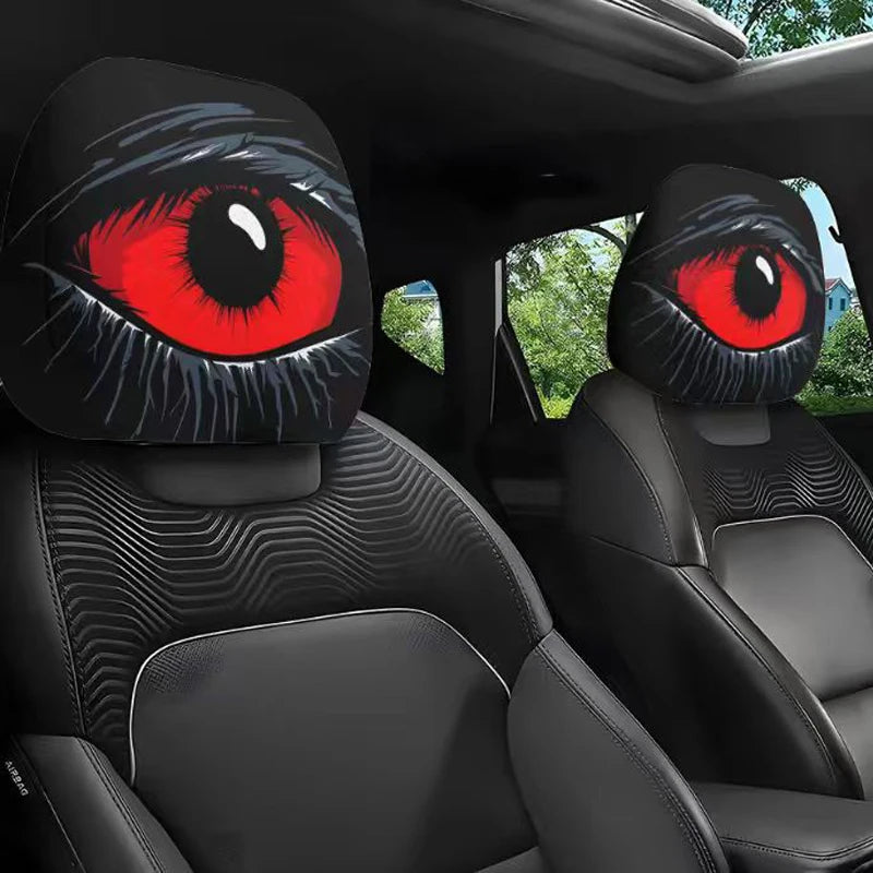 A pair of car headrest covers featuring realistic, slanted eye designs in black and vibrant red.