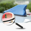 A magnifying glass shows a blue carbon fiber look roof mount antenna component.
