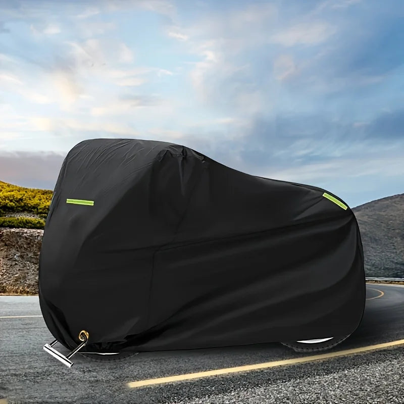 Black motorcycle cover with yellow reflective strips lying on an asphalt road.