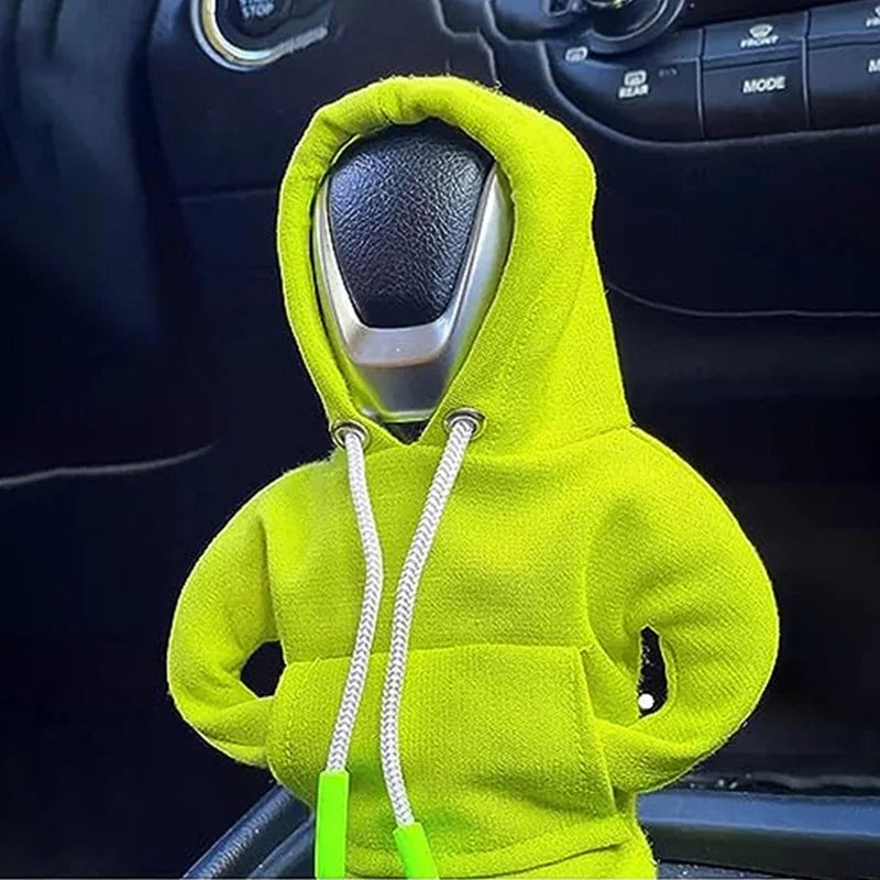 A bright lime green hoodie is placed over a gear shift cover in a car interior.