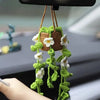 A hanging crochet strawberry decor featuring green leaves and white flowers, suspended from a black hanger.