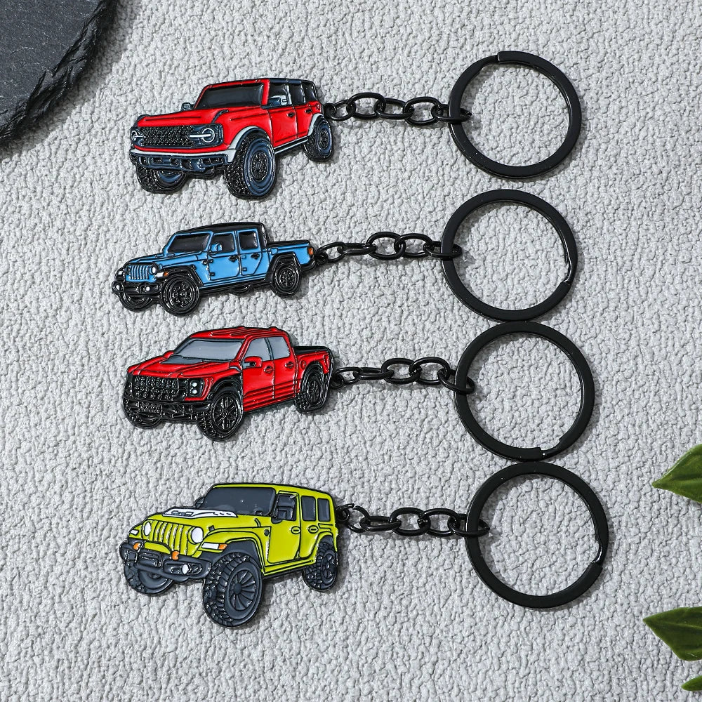 Four metal alloy car keychains in red, blue, orange, and yellow are displayed against a textured gray background.