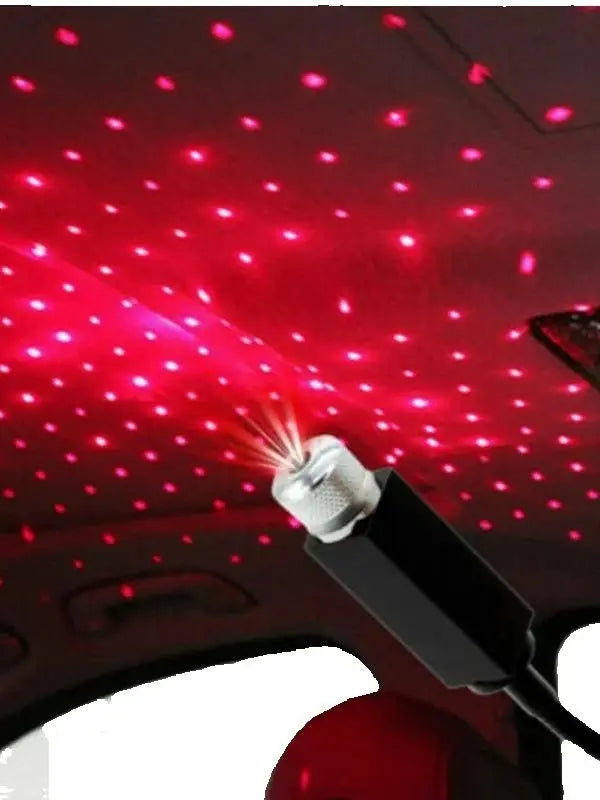 A portable LED star projector night light shining bright red dots onto a car's interior ceiling.