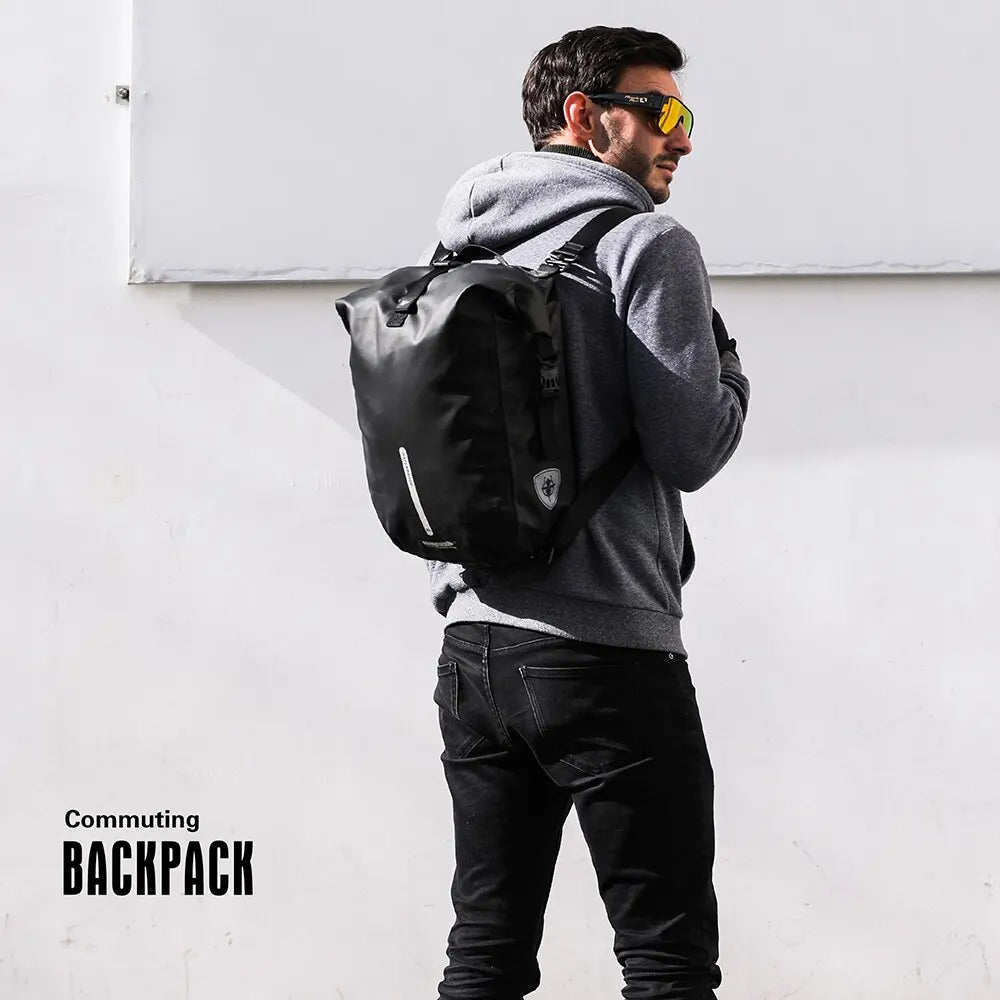 A man wearing a grey hoodie and sunglasses is carrying a black commuting backpack.