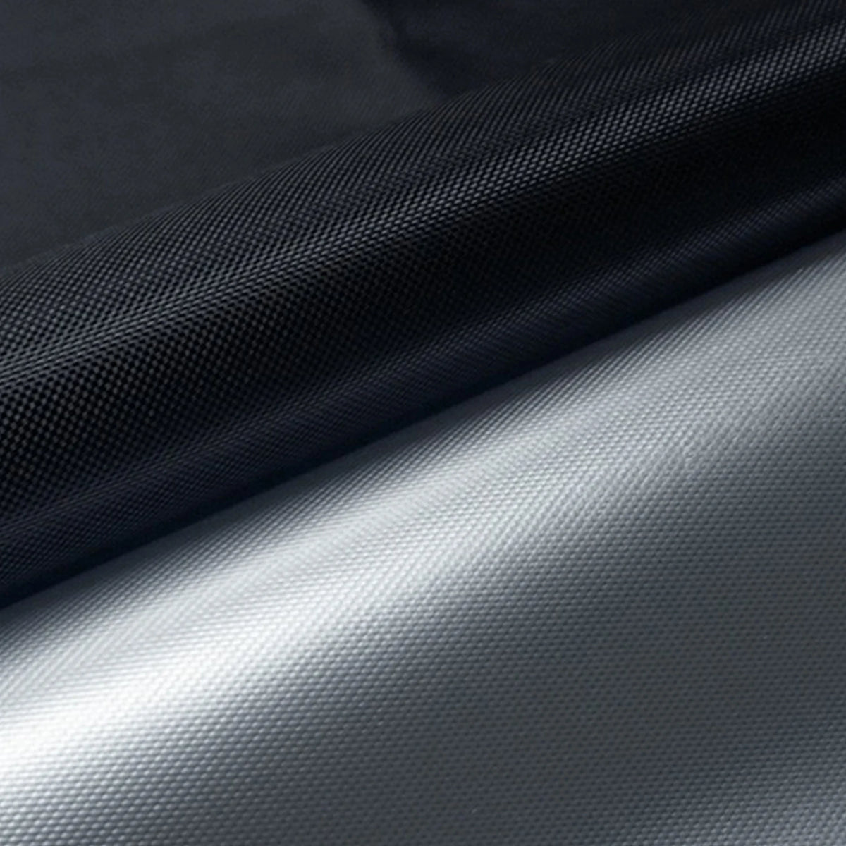 A close-up of a black blackout sunscreen window shade rolled up, showing its texture and smooth finish.