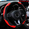 A black steering wheel with a red PU carbon fiber cover installed in a car interior.