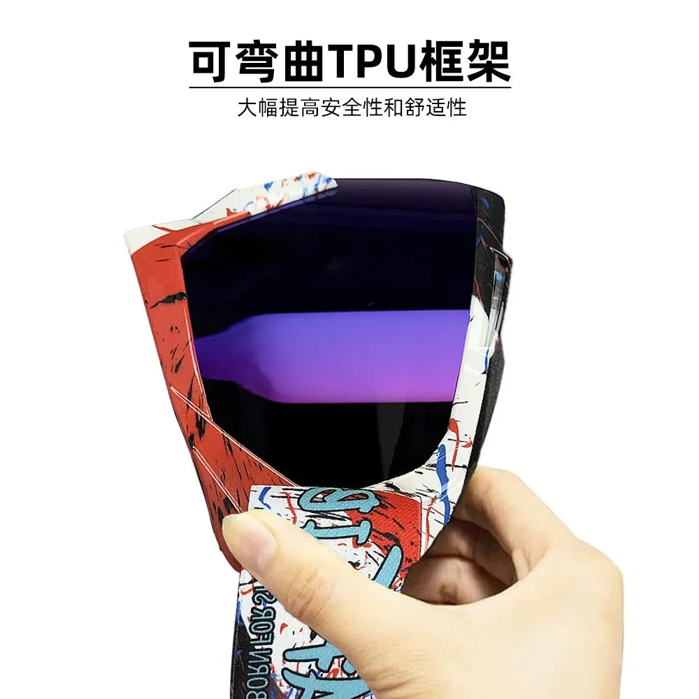 A hand holds a pair of red and white patterned TPU-framed motorcycle goggles.