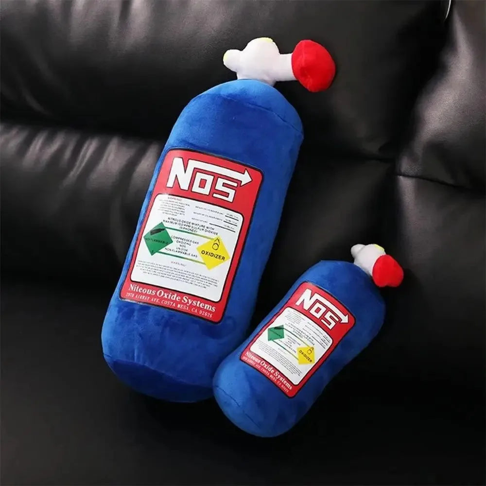 A blue pillow shaped like a nitrous oxide bottle with a red cap and a green label, resting on a dark surface.