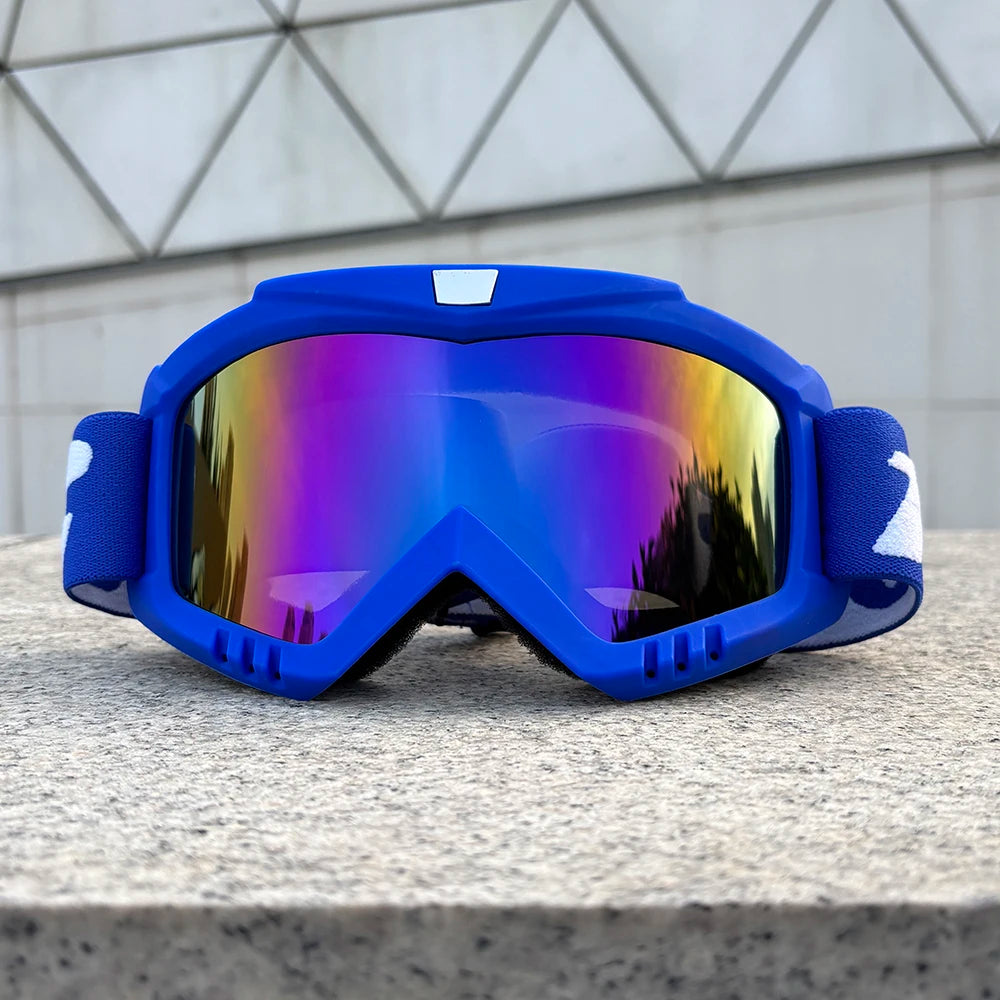 A pair of bright blue windproof sports goggles with mirrored lenses resting on a gray stone surface.