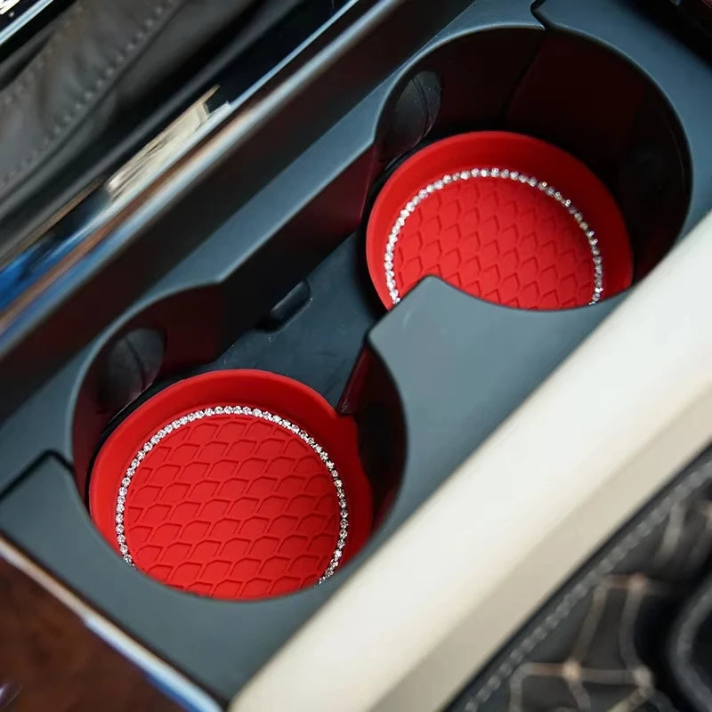 A close-up view of a red rhinestone car cup holder coaster insert in a dark gray automotive storage compartment.