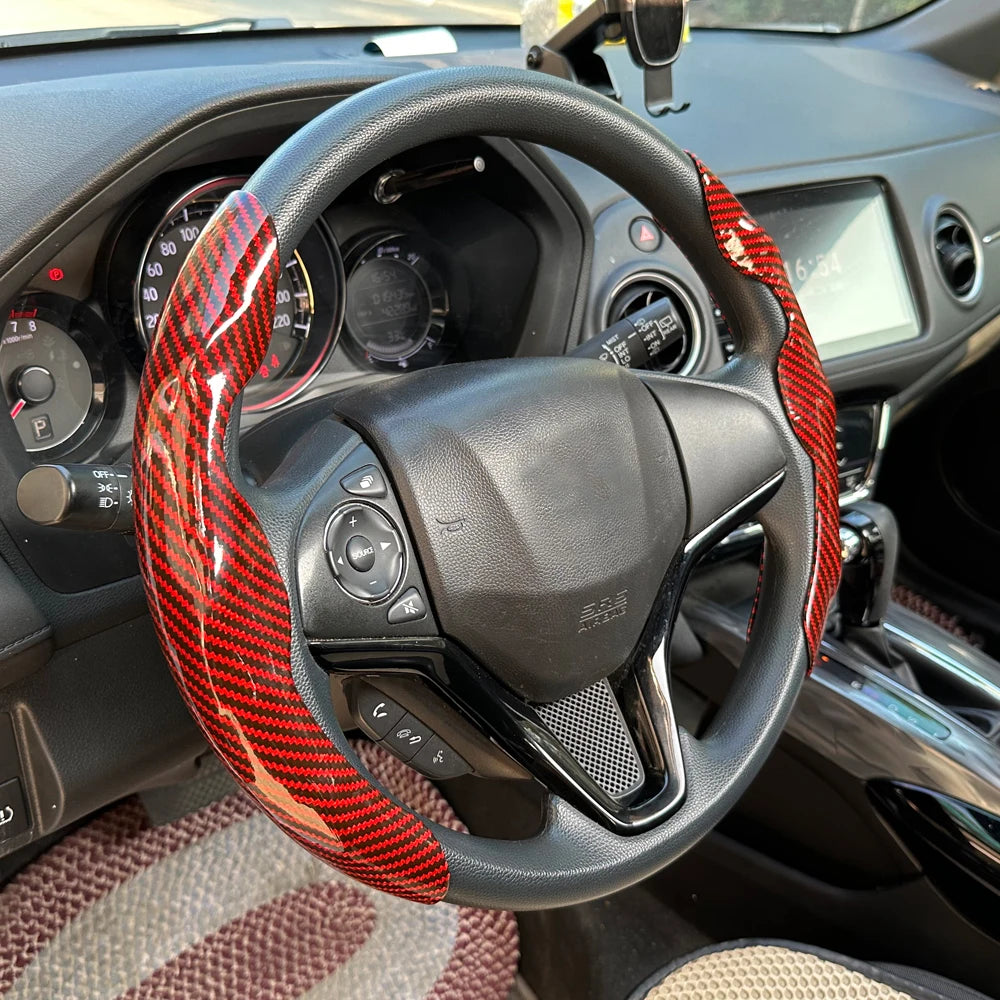 A black steering wheel with a red and black patterned booster cover installed in a car interior.