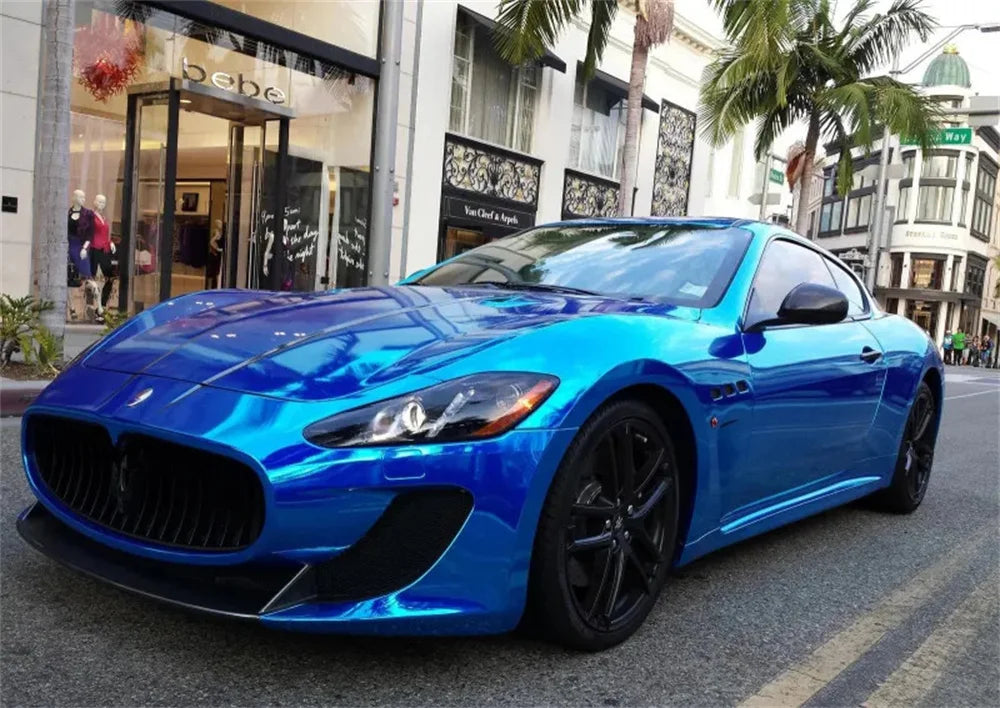 A bright blue muscle car parked on a street with storefronts in the background.