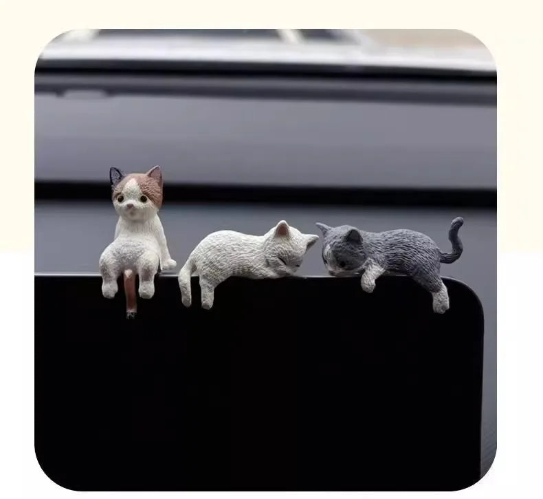 Tres gatitos de diferentes colores y tonos sentados sobre una superficie oscura.
