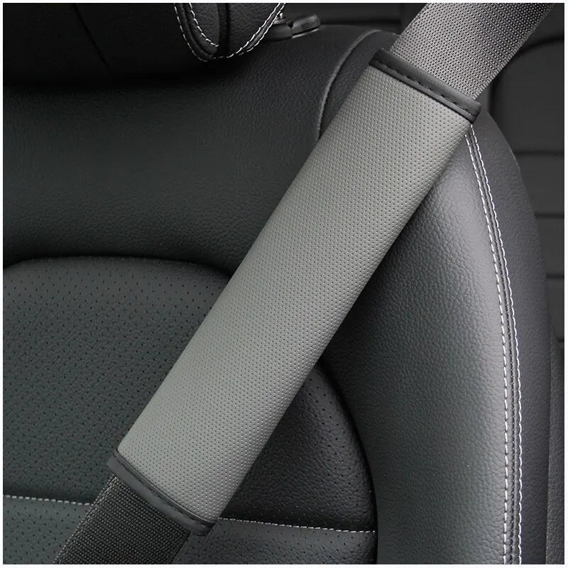 Gros plan d'une housse de ceinture de siège en cuir PU gris embossé sur un siège de voiture foncé.