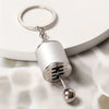 Silver keychain featuring a cylindrical metal component with an engraved symbol and a spherical charm.