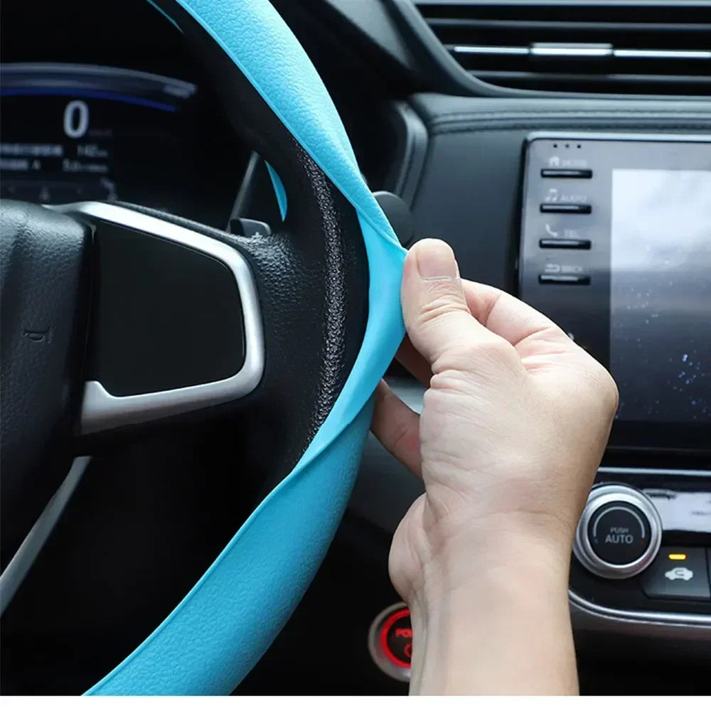A hand is adjusting a bright blue silicone steering wheel cover on a black car steering wheel.