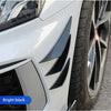 Close-up of a white car's front fender and wheel showing bright black spoiler fins.