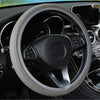 Close-up view of a black steering wheel with a light gray anti-slip leather cover inside a car interior.