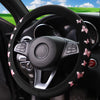 Black steering wheel with a glitter butterfly patterned non-slip cover inside a car