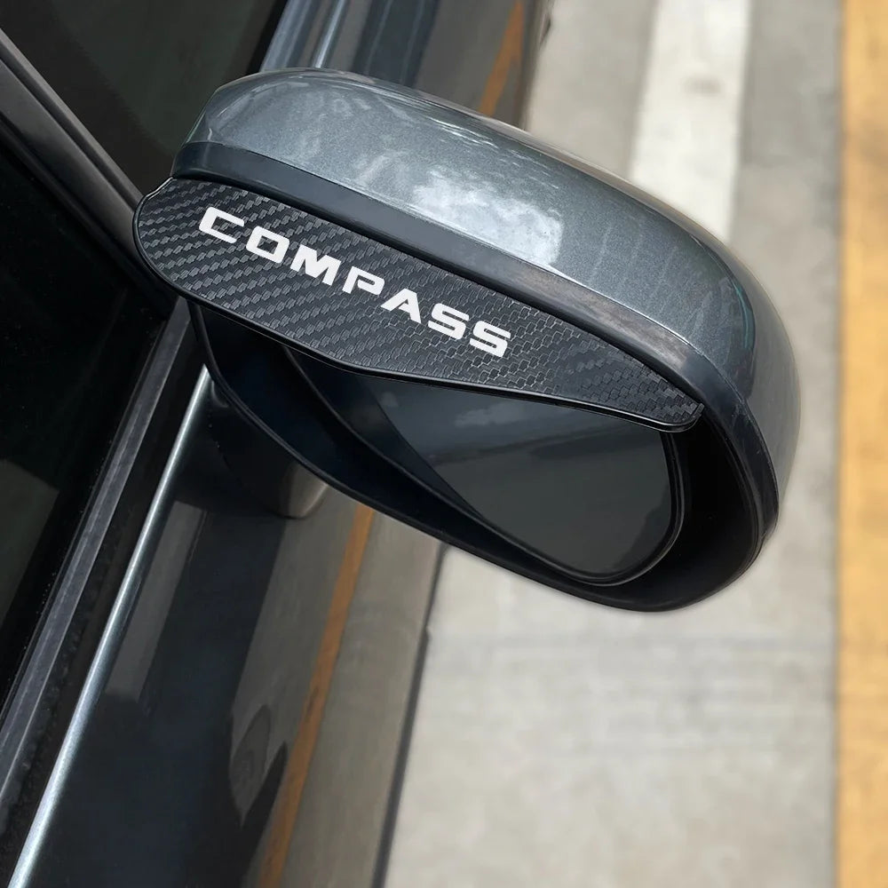 A black carbon fiber texture rain visor is shown attached to a car's rearview mirror.