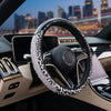 Close-up of a black steering wheel with a leopard print cover and gold accents inside a car interior.