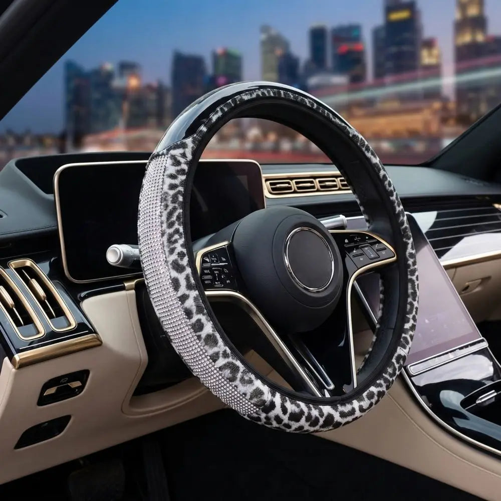 Close-up of a black steering wheel with a leopard print cover and gold accents inside a car interior.