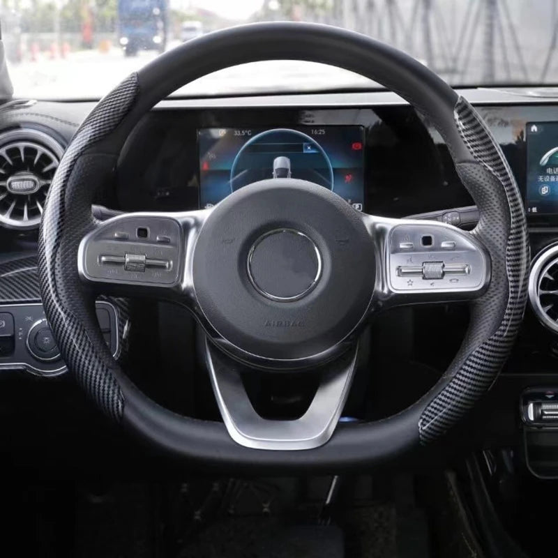 Close-up view of a black steering wheel with carbon fiber grips and controls inside a car