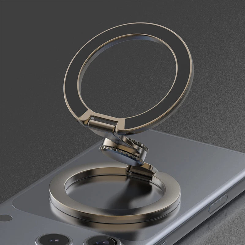 A close-up of a bronze magnetic phone ring stand with a dual-sided grip resting on a smartphone.