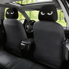 A set of two black car headrest covers with angry eyes installed in a vehicle interior.