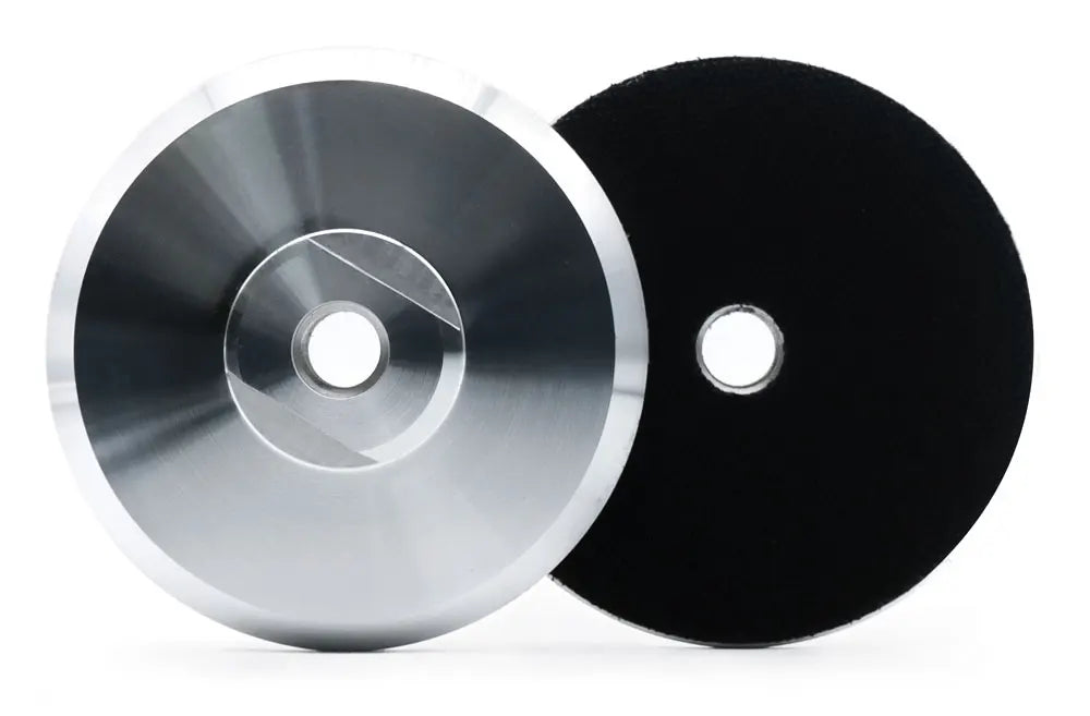 Un pad de support en aluminium argenté et un pad de polissage noir présentés côte à côte.