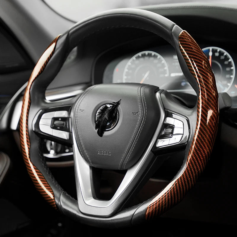 Gros plan d'un volant noir avec une gaine de grip en fibre de carbone orange et le logement de l'airbag.