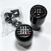 A black gear shift knob with the markings 135 246 R is shown next to a clear plastic bag containing spare knobs.