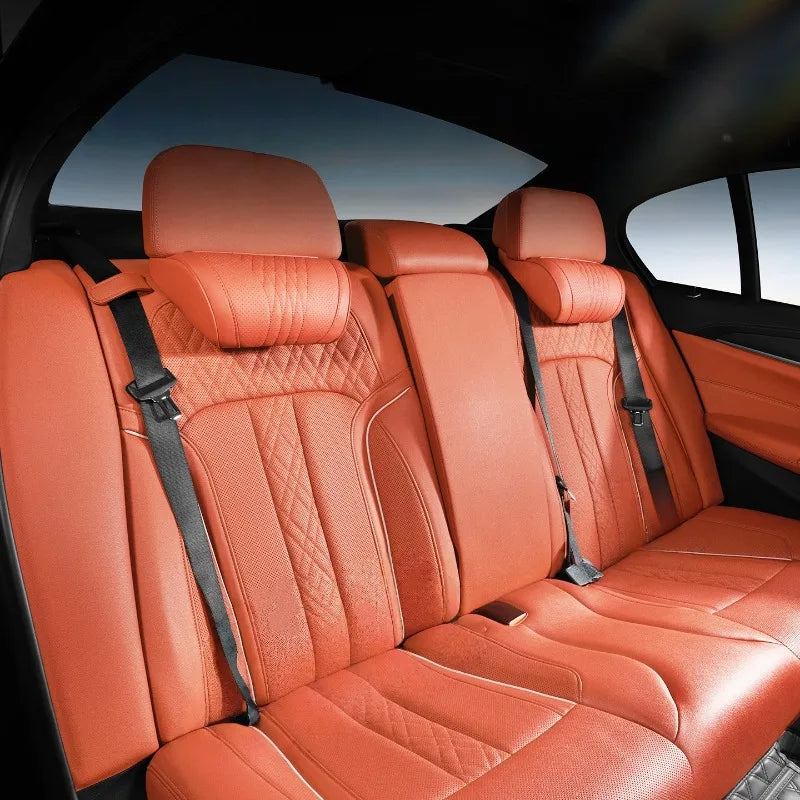 Interior view of a car seat showing orange leather headrests and seat upholstery.