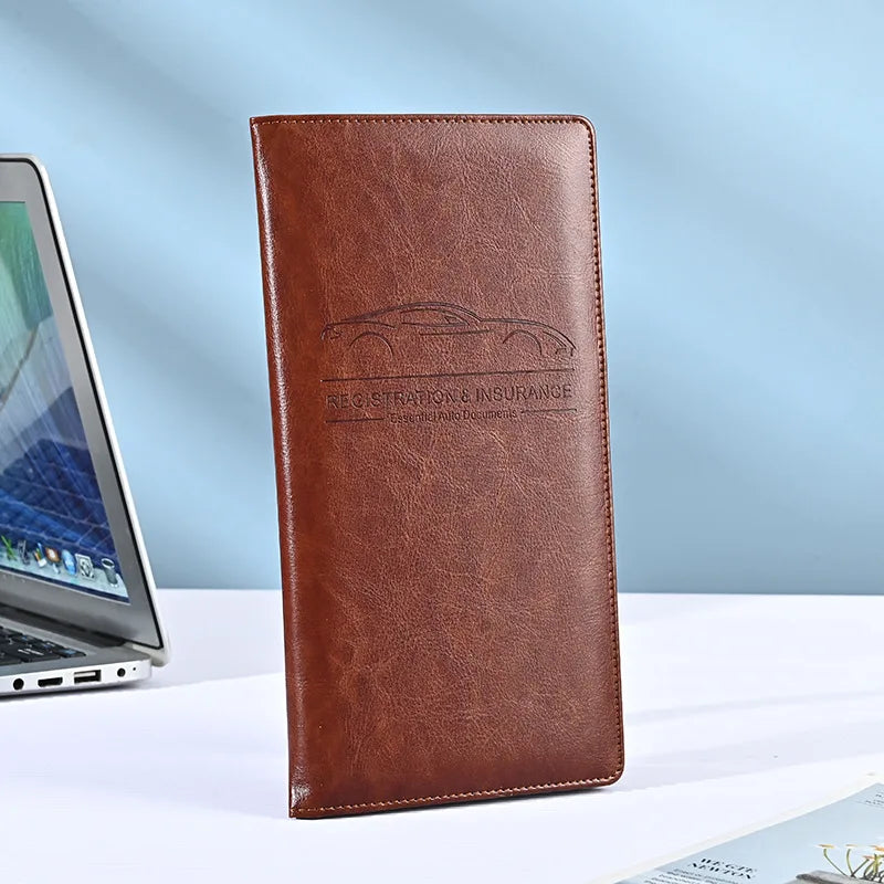 A brown leather vehicle organizer wallet with embossed text on a white surface.