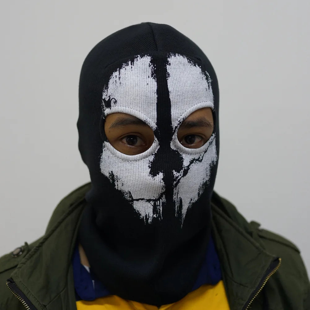 Una persona con una máscara balaclava negra de cara completa con marcas tribales blancas, parcialmente visible bajo una chaqu
