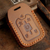 A brown leather key cover with embossed symbols for Chevrolet and GMC trucks resting on a wooden surface.