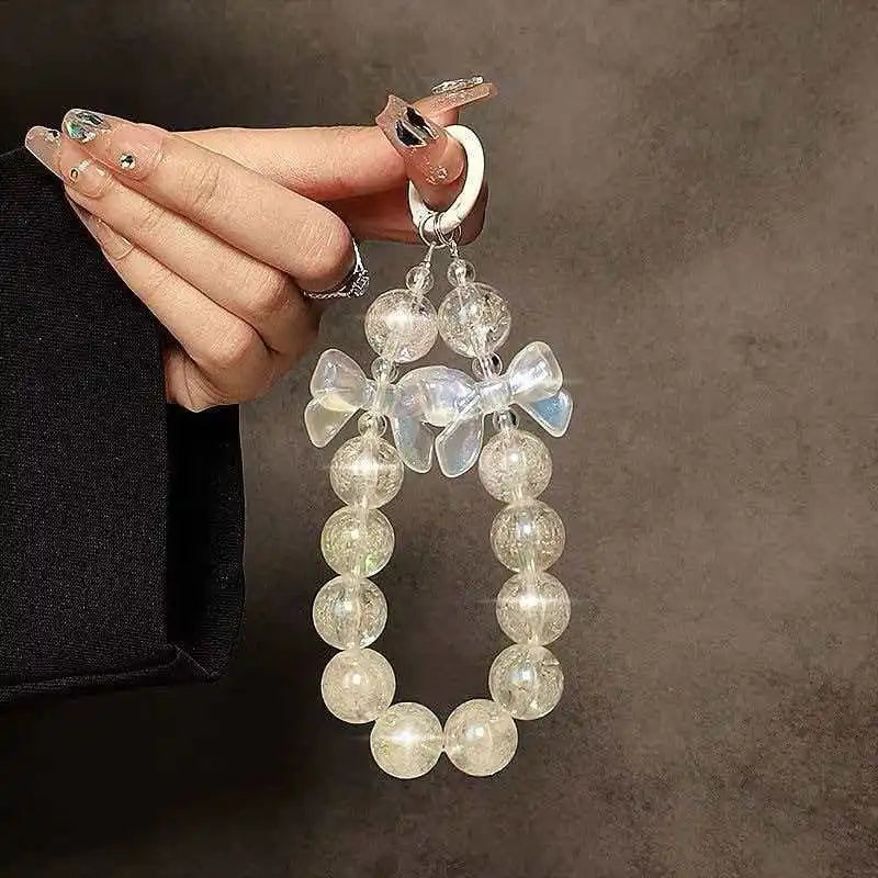 A hand is holding a silver phone anti-loss lanyard with a round bead pendant featuring a floral charm.