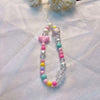 A lanyard featuring a round bead pendant with various colored beads and a charm on a white fabric background.