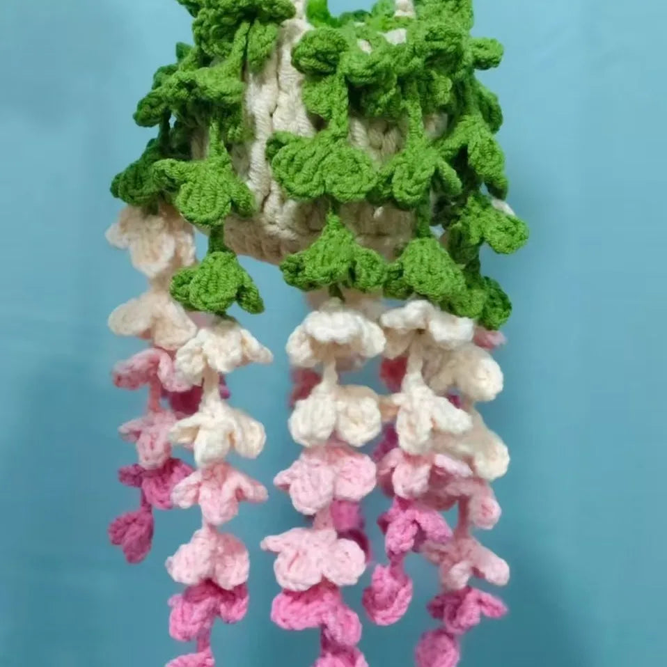 A hanging crochet strawberry decor featuring green and pink floral elements.